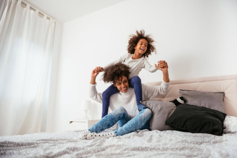 Does an AC Kill Mold? Mom and daughter playing on a bed.