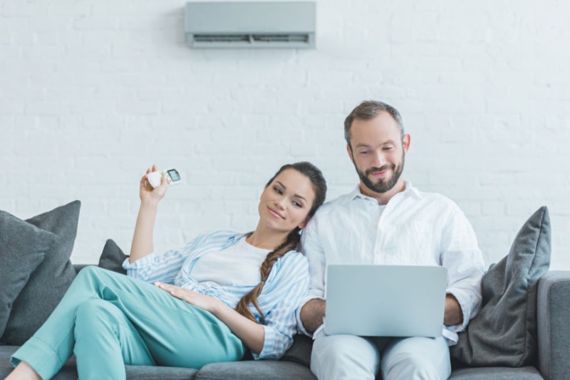 a man and woman sitting on a couch with a laptop.