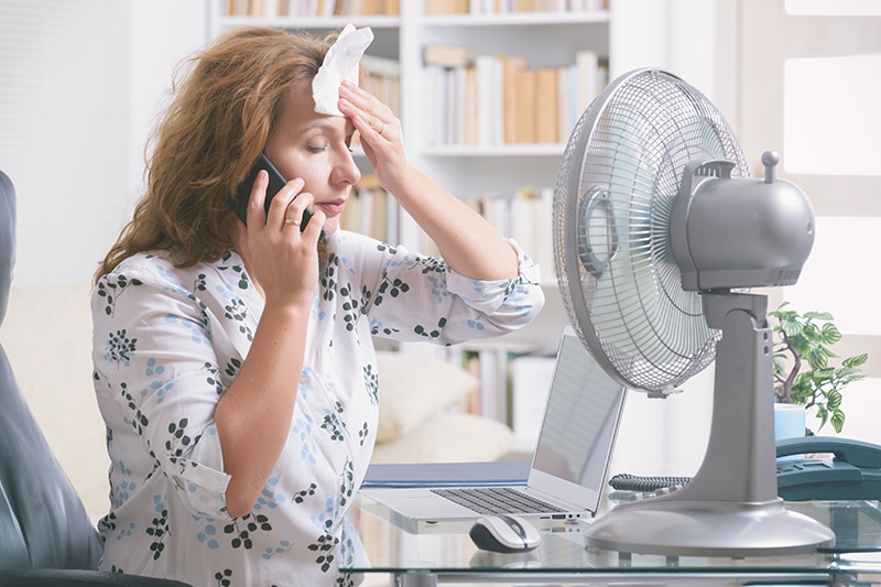 When Do I Replace My Air Conditioner? - Woman Wipes Sweat off Her Face By the Fan.