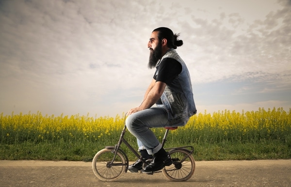 Bearded man is sitting on a small bicycle