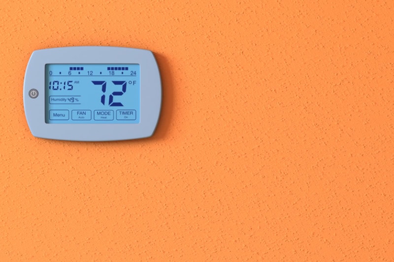 Thermostats 101. One orange wall with a digital thermostat panel.